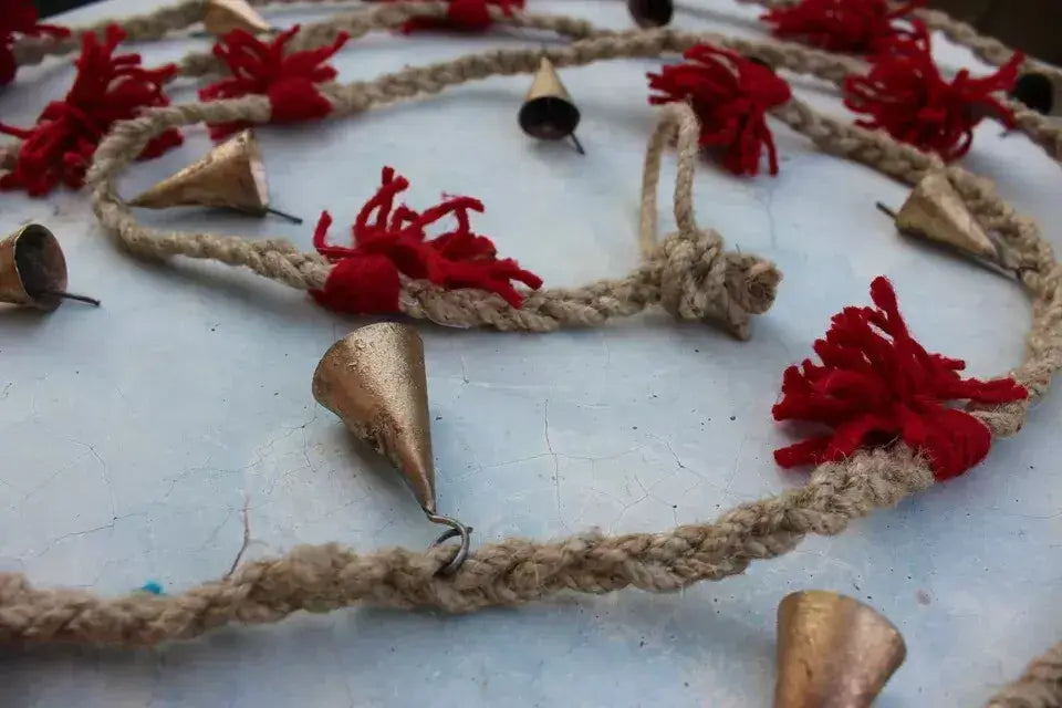 Vintage cow bells on jute string with wool tassels, perfect for rustic garden decor, outdoor mobile, or festive party decoration.