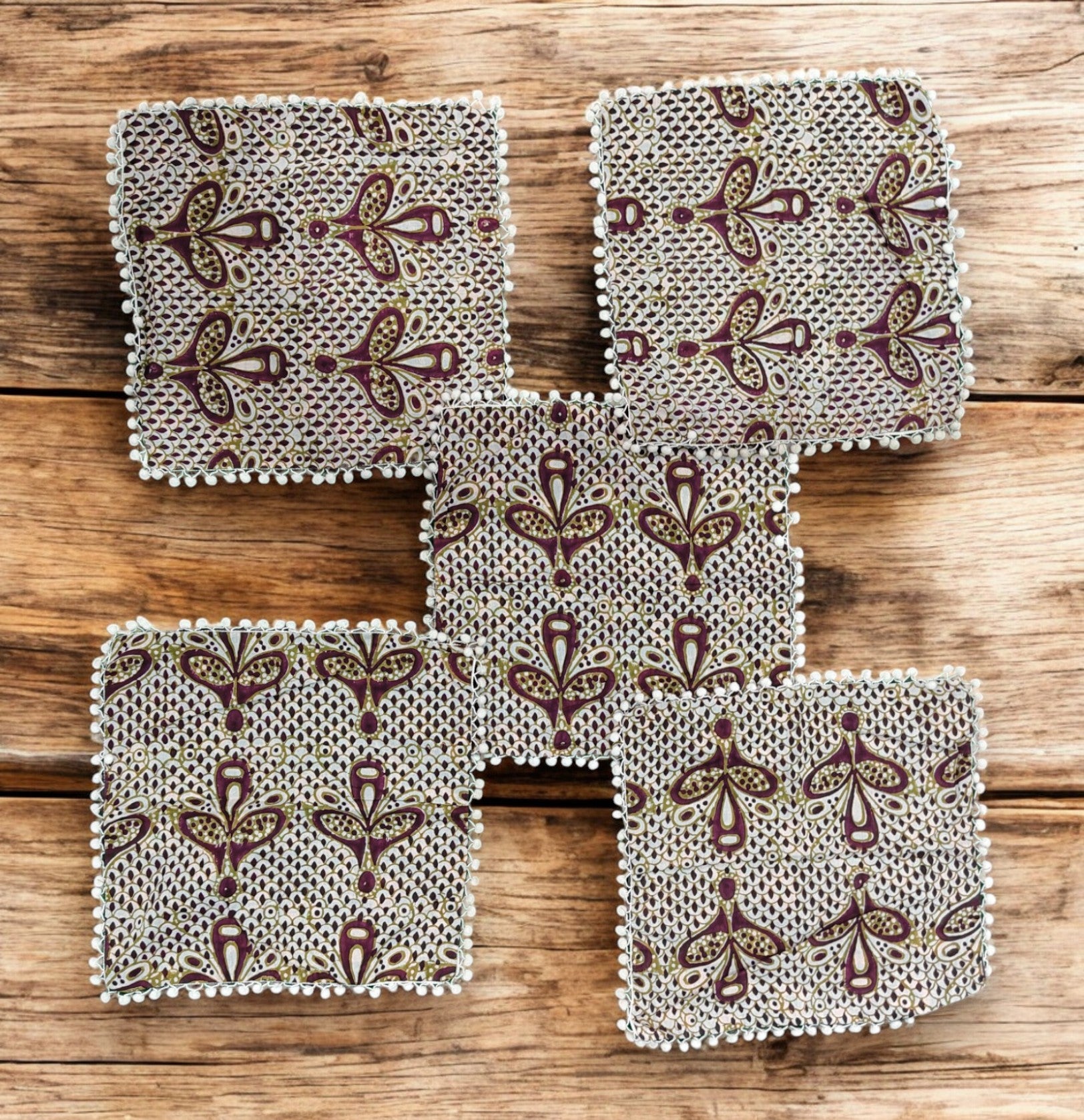 Set of 5 decorative cushion covers with ethnic floral design on a rustic wooden surface.