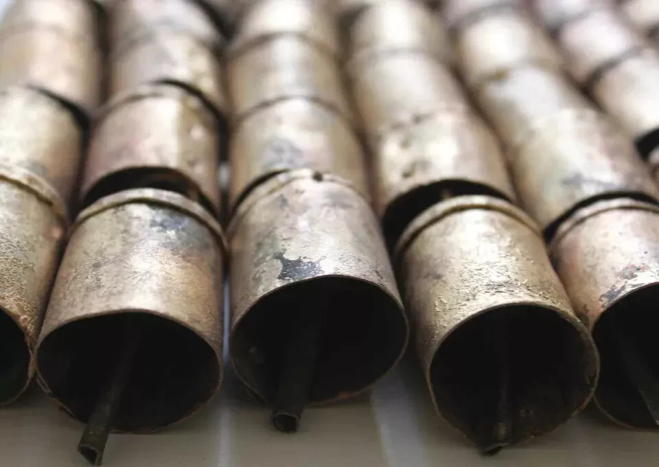 Handmade Indian cowbells made from recycled iron, featuring a rustic brass finish, closely arranged in a line.