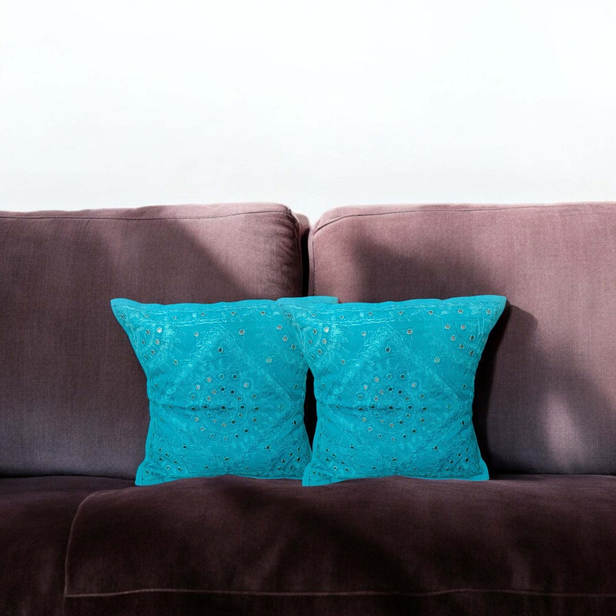 Set of 2 turquoise blue mirror work cushion covers on a brown sofa, perfect for home decor accent pillows.