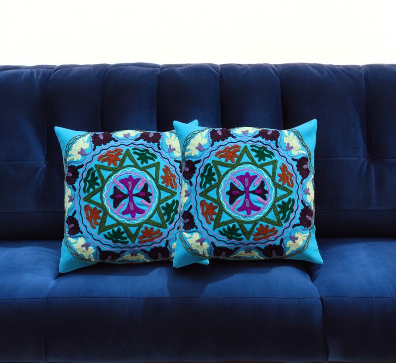 Set of 2 vibrant decorative cushion covers with intricate patterns on a blue sofa, perfect for home accents.