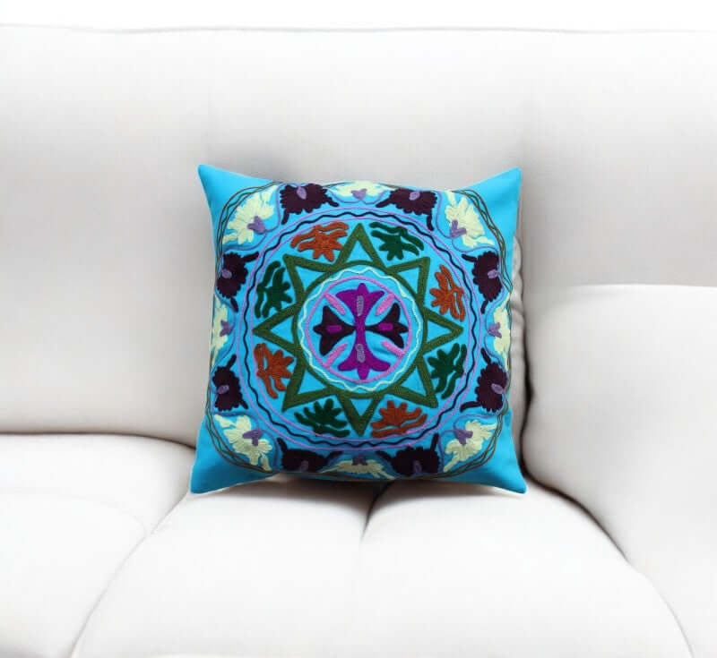 Vibrant multicolor decorative cushion cover with intricate mandala design on a white sofa.