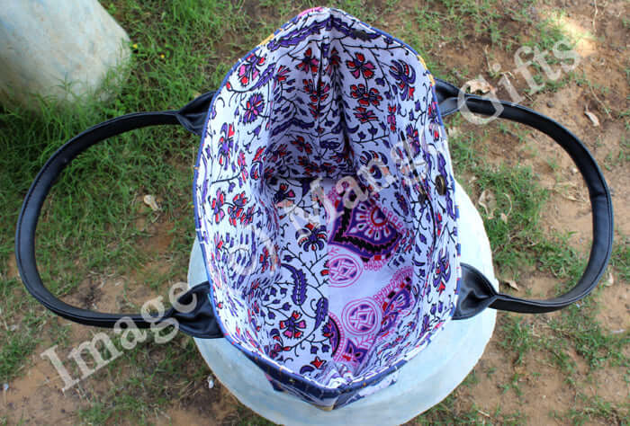 Inside view of a handmade blue cotton tote bag showcasing vibrant floral patterns and durable black leather straps.