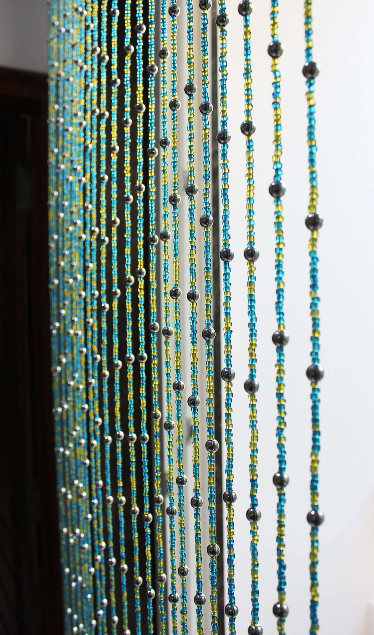 Handmade colorful glass bead strands with jingle bells—perfect for doorways or wall décor. Eco-friendly and crafted by women's artisans in India.