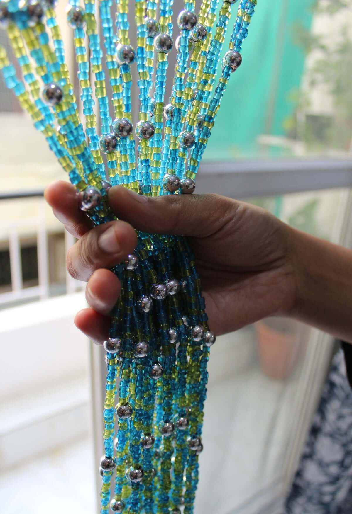 Handmade colorful glass bead strands with jingle bells—perfect for doorways or wall décor. Eco-friendly and crafted by women's artisans in India.