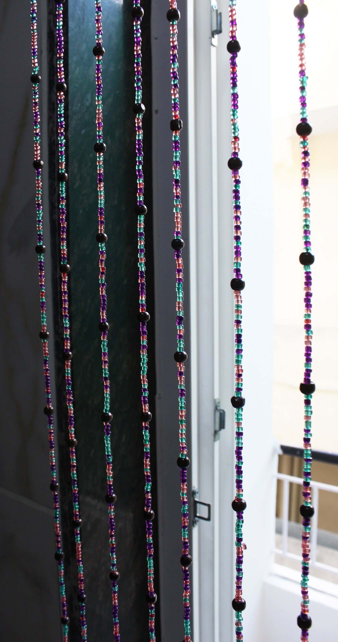 Handmade colorful glass bead strands with jingle bells—perfect for doorways or wall décor. Eco-friendly and crafted by women's artisans in India.