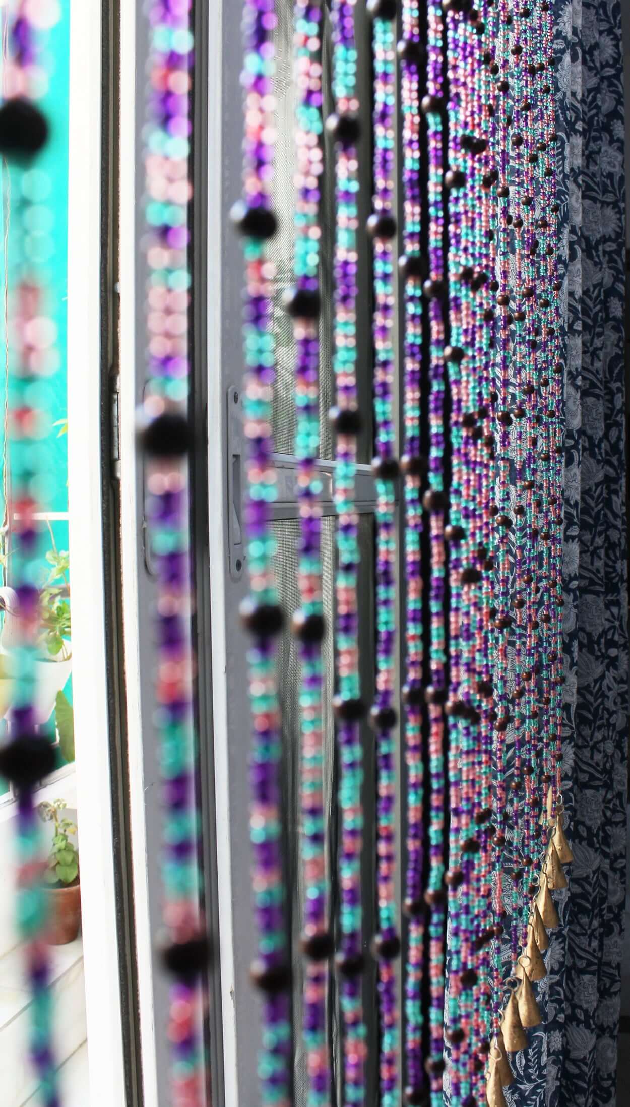 Handmade colorful glass bead strands with jingle bells—perfect for doorways or wall décor. Eco-friendly and crafted by women's artisans in India.