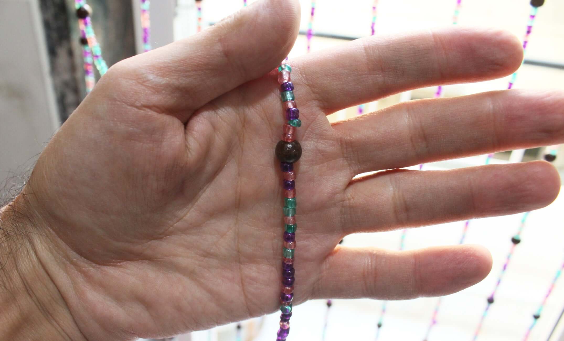 Handmade colorful glass bead strands with jingle bells—perfect for doorways or wall décor. Eco-friendly and crafted by women's artisans in India.