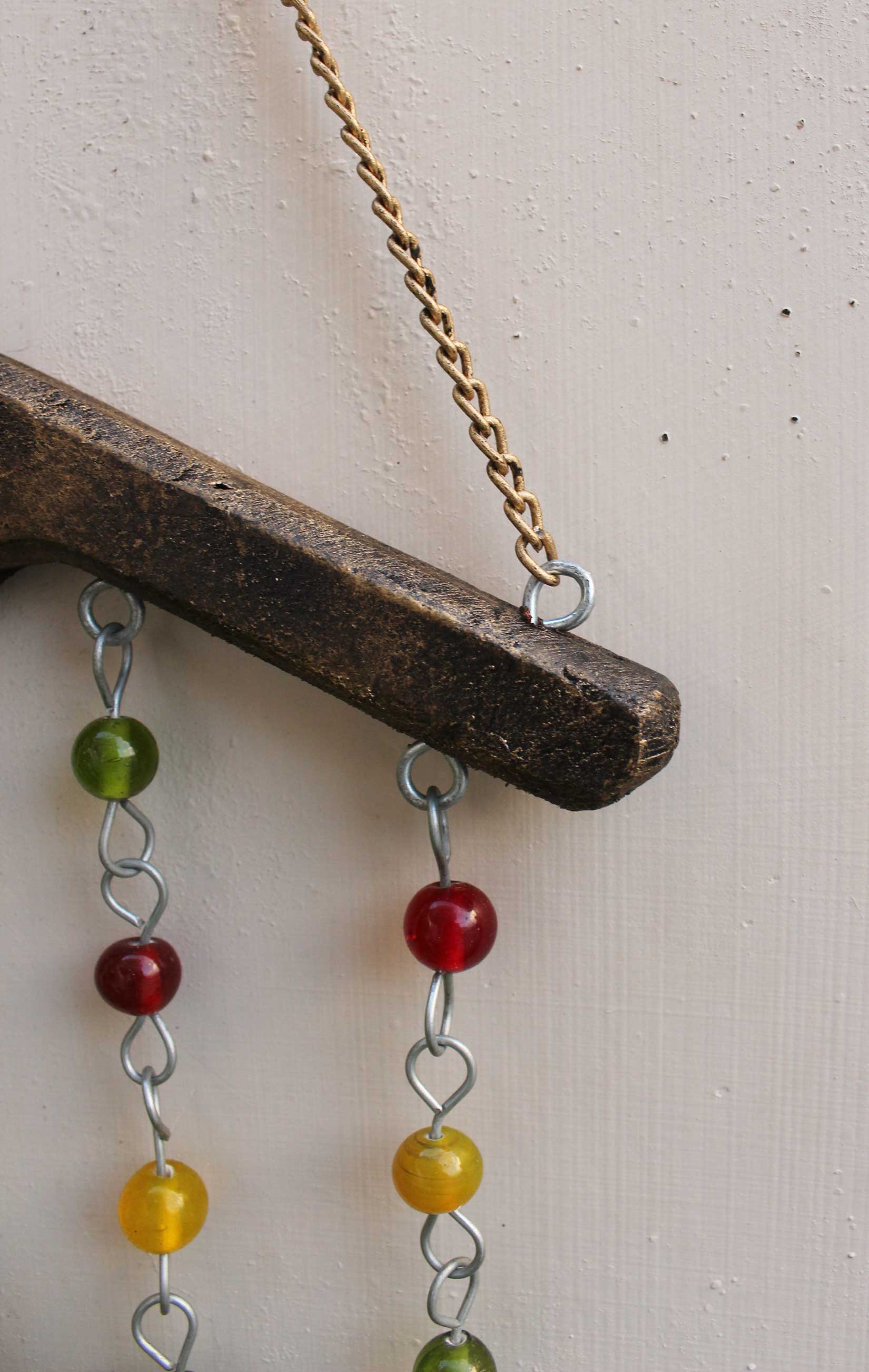 Handmade hanging chime with colorful glass beads and tin bells, perfect for indoor or outdoor decoration.