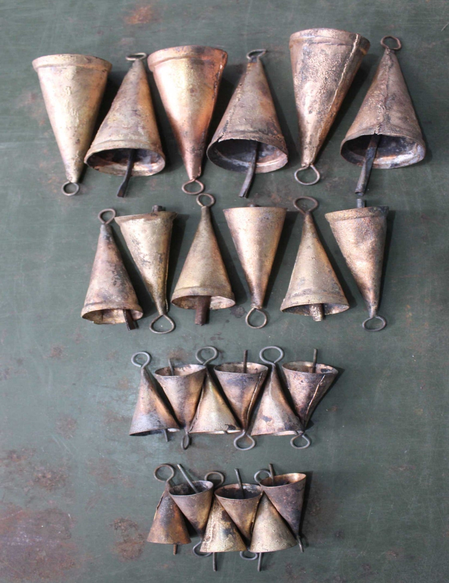 Set of 24 handmade recycled iron decorative cone bells in vintage brass finish, showcasing unique rustic colors.
