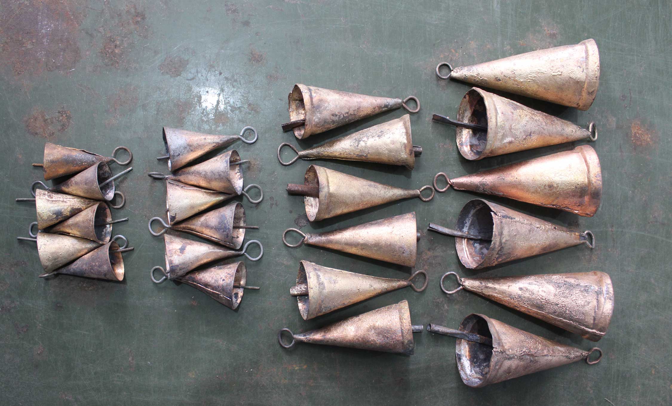 Set of 24 handmade recycled iron cone bells in rustic golden and brown shades, showcasing unique variations.
