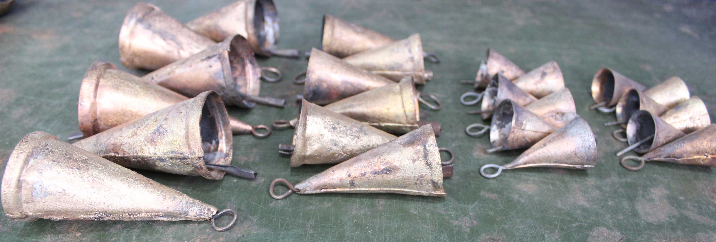 Set of 24 handmade vintage recycled iron cone bells in various sizes, showcasing rustic brass finish.