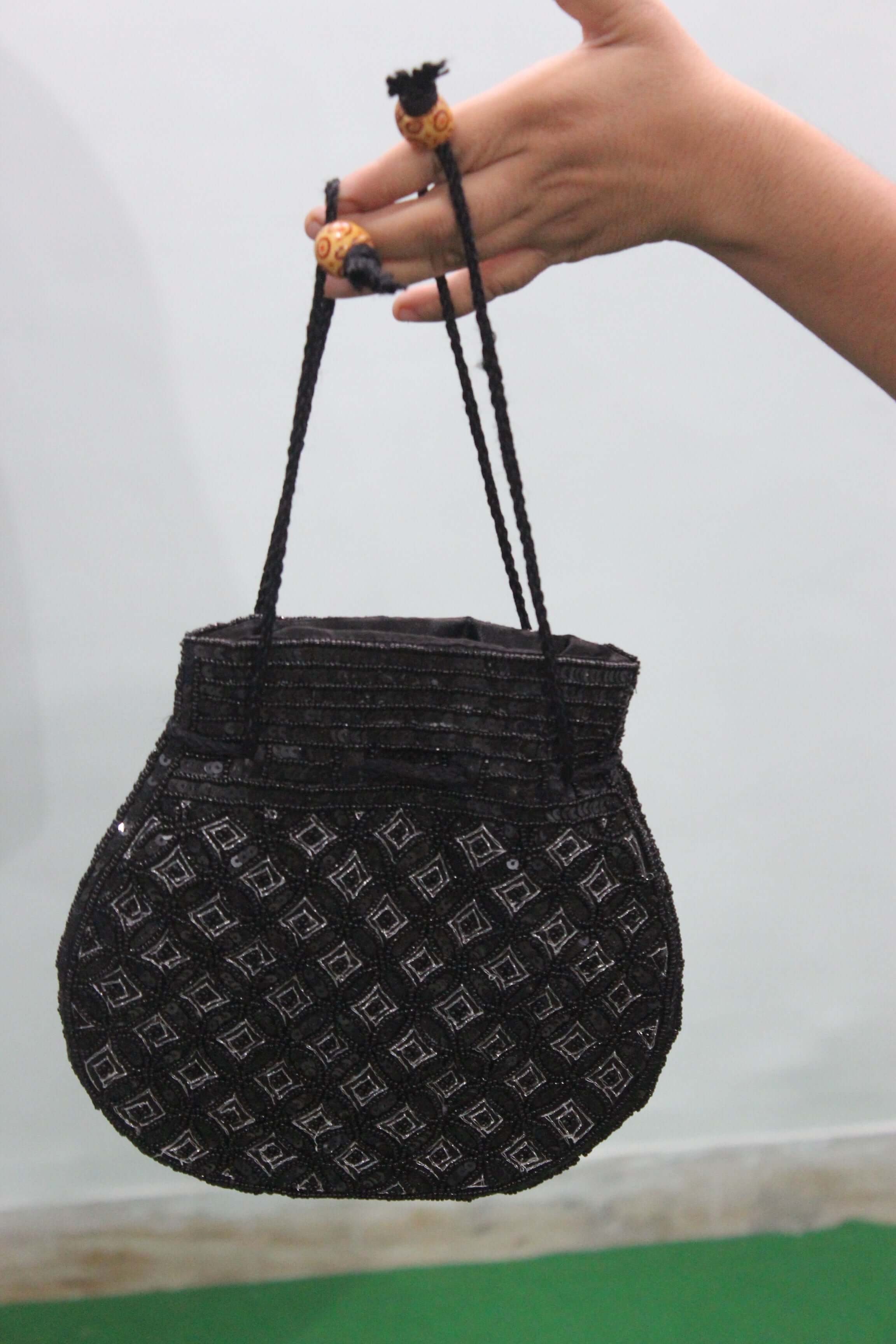 Beautiful black handmade Indian potli bag with sequins, featuring two small handles and stylish design.