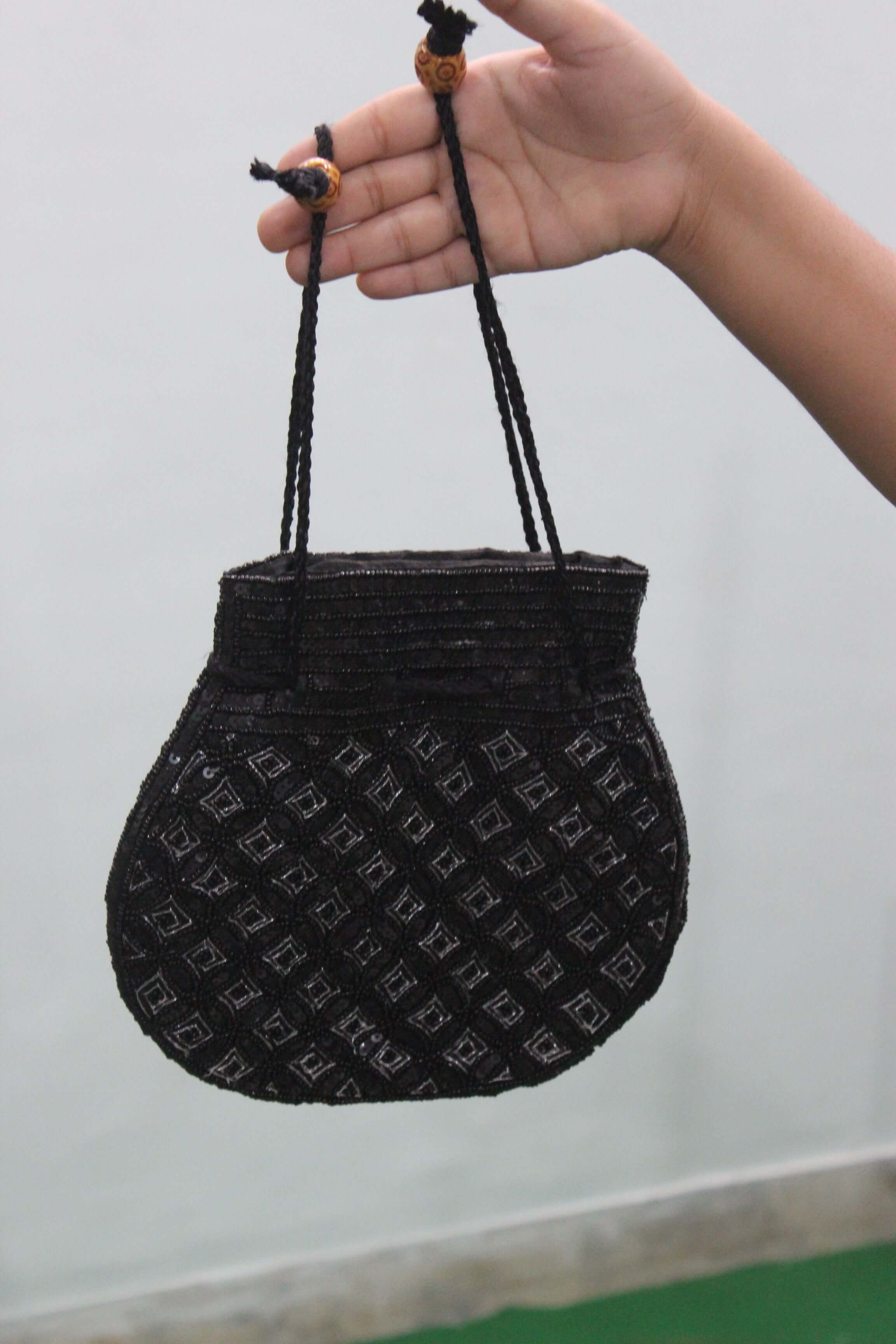 Handmade black Indian potli bag with sequins, perfect for fashion and small articles, shown in hand.