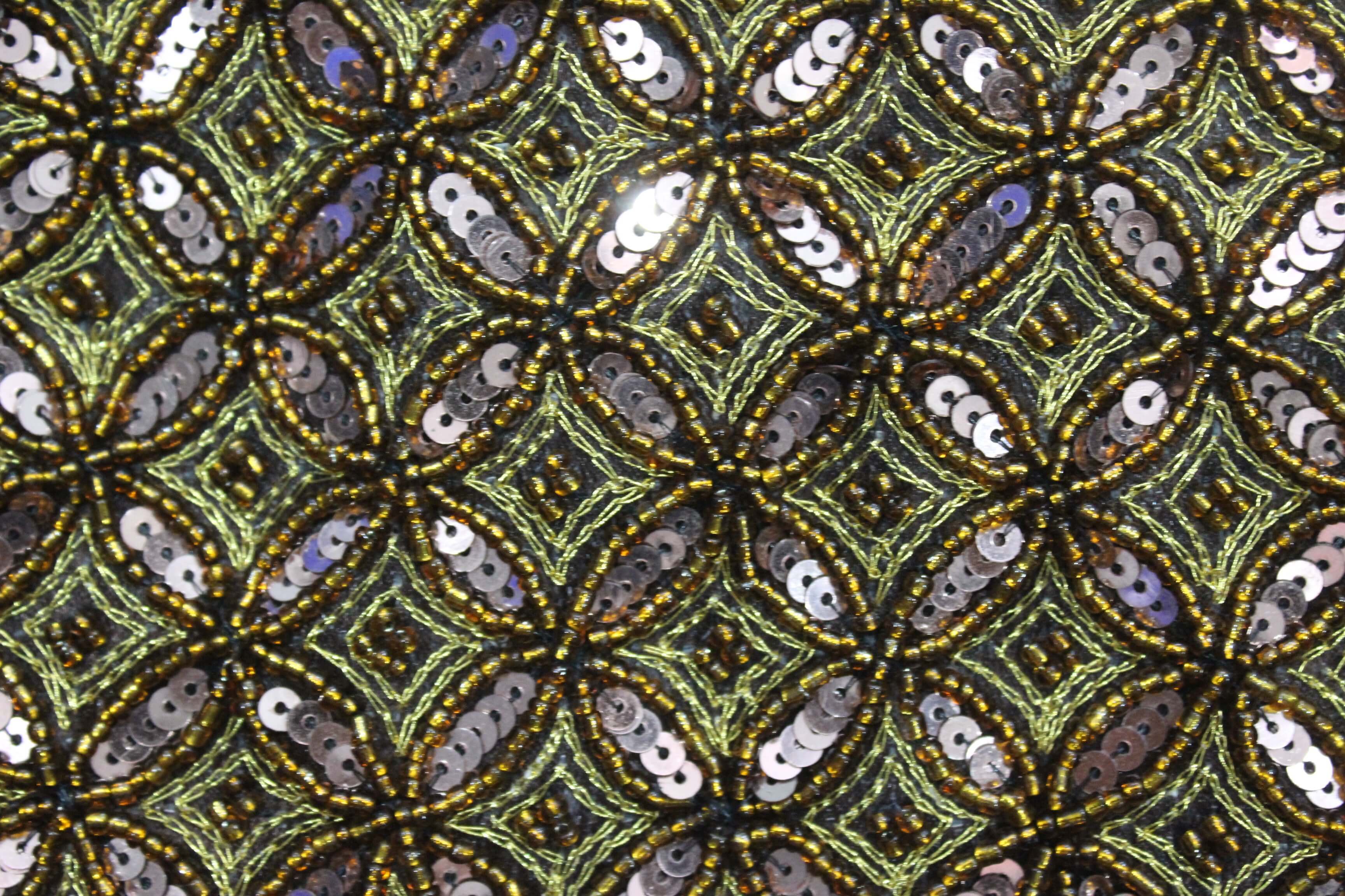Close-up of intricate golden and silver sequin pattern on fabric, perfect for festive accessories and party wear.