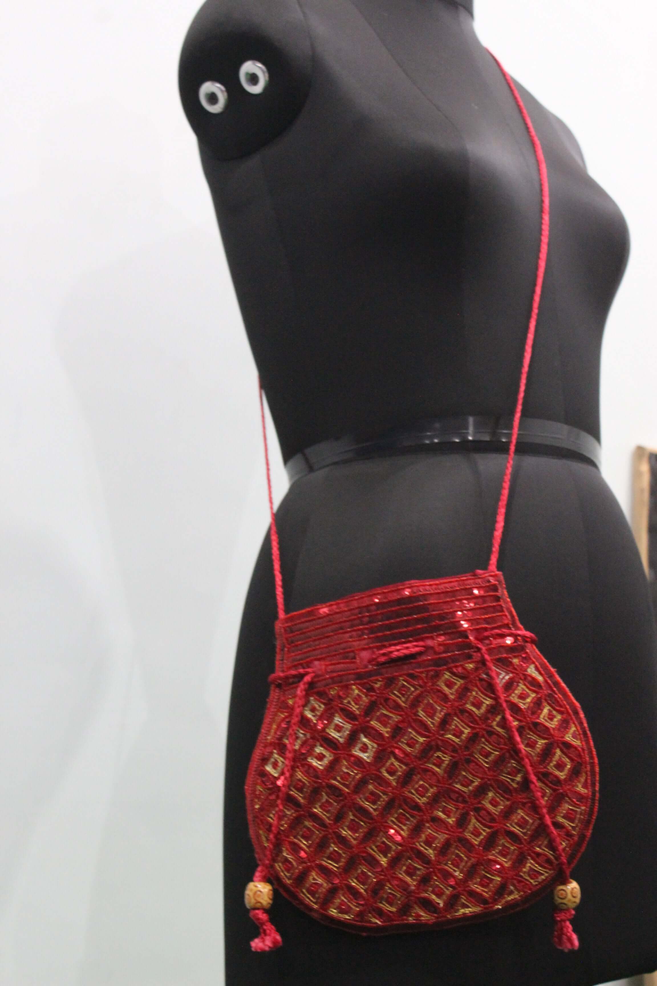 Beautiful red handmade Indian potli bag with sequins, stylishly worn as a sling bag.