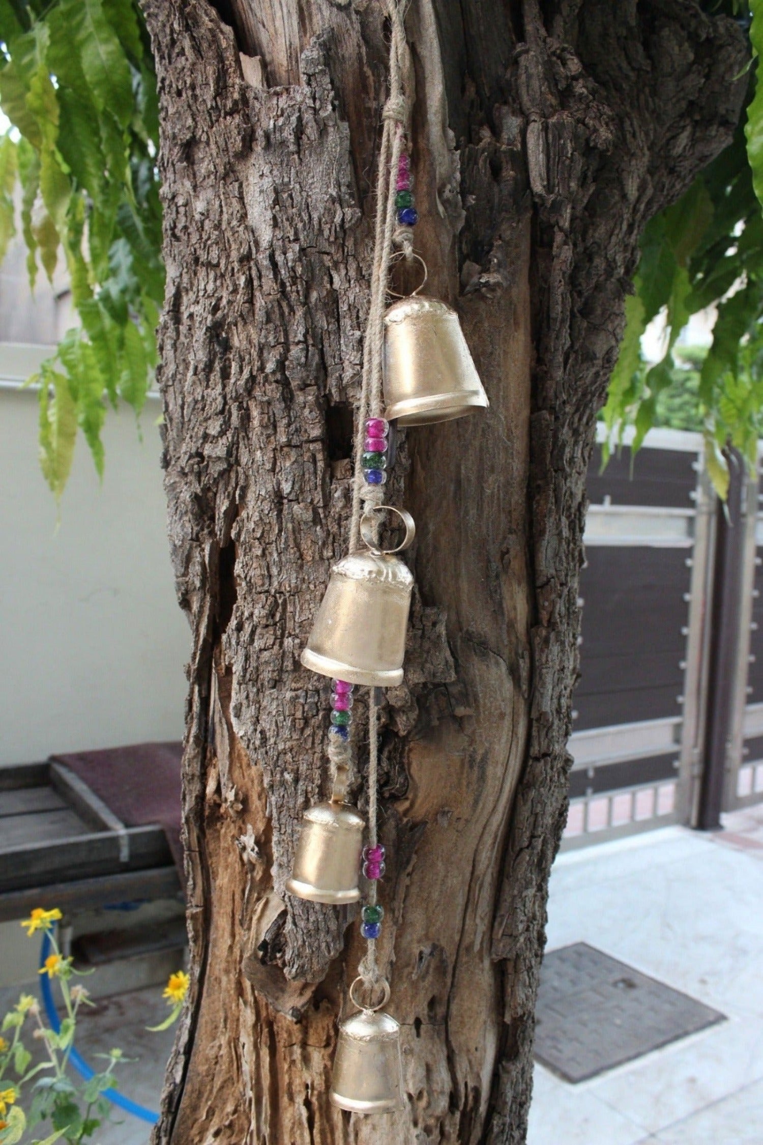 Handmade tin bells hanging chime with jute string and glass beads for outdoor garden decoration.