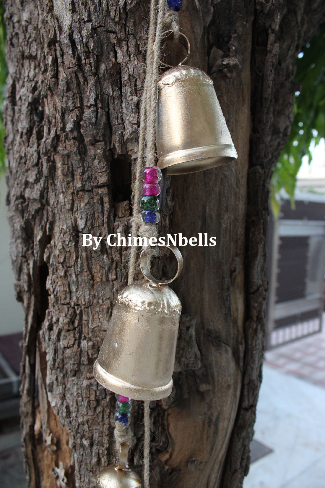 Handmade iron tin bells on jute string with glass beads, perfect for outdoor garden patio decoration.