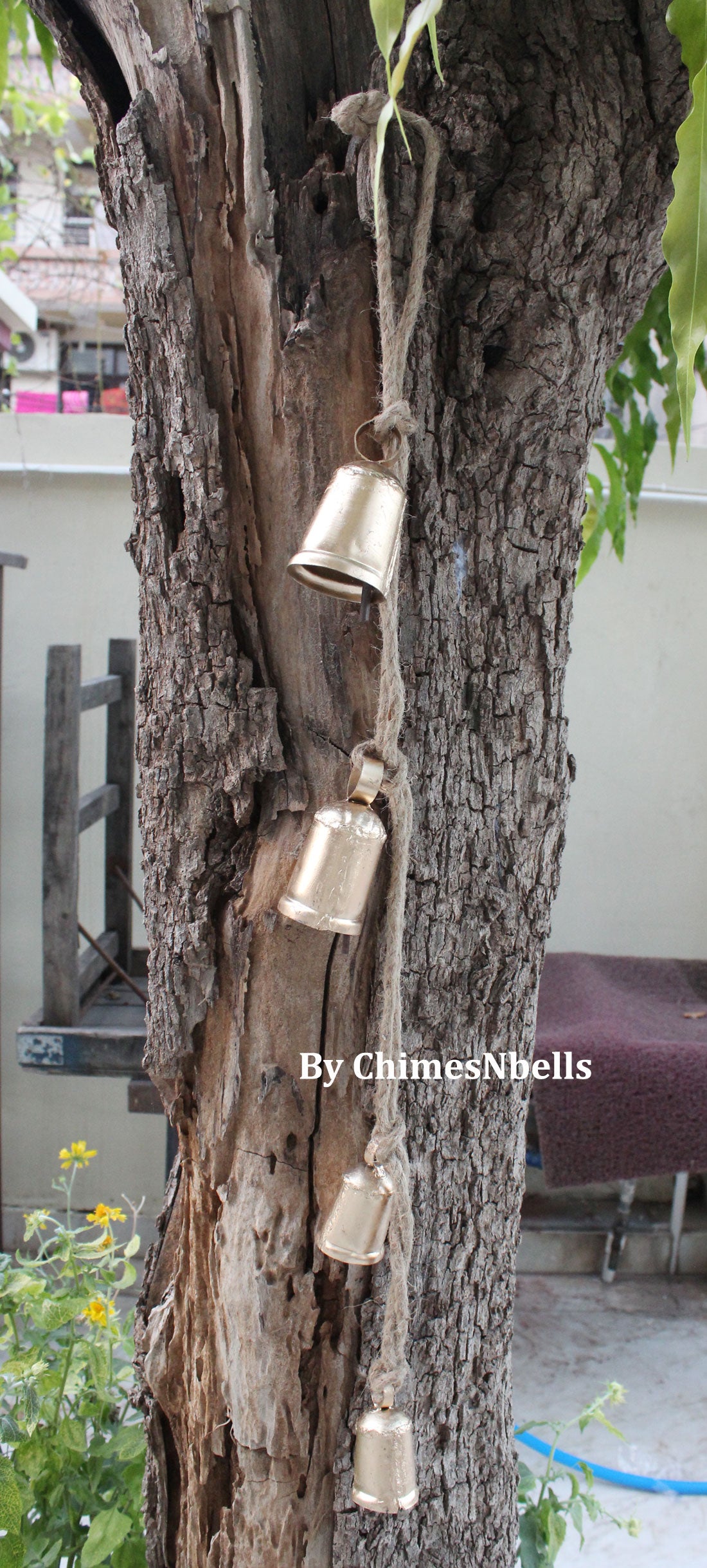 Handmade tin bells hanging chime on tree, perfect for outdoor patio and garden decoration, creating soothing sounds.