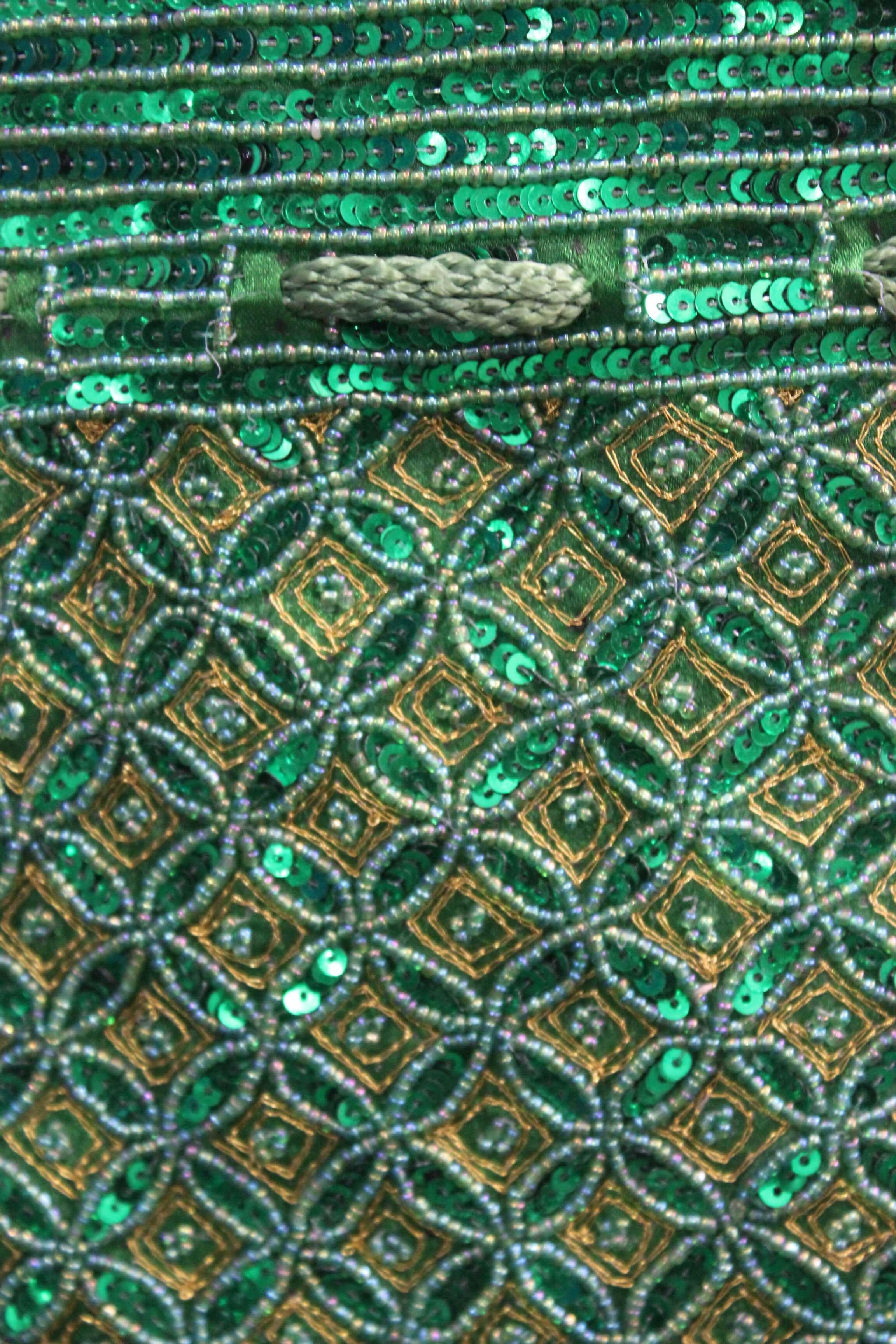 Close-up of a beautiful green handmade Indian potli bag adorned with sparkling sequins, showcasing intricate design patterns.