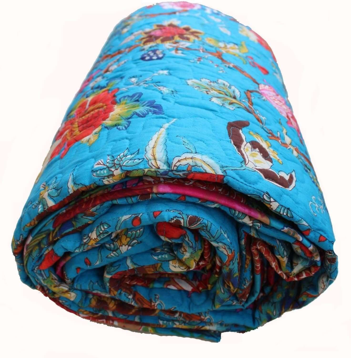 Rolled blue floral reversible cotton quilt with vibrant patterns, perfect for cozying up any space.