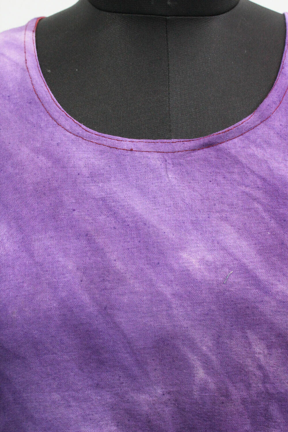 Close-up of cotton tie-dye pattern in vibrant purple color, showcasing the neckline of a boho maxi dress.